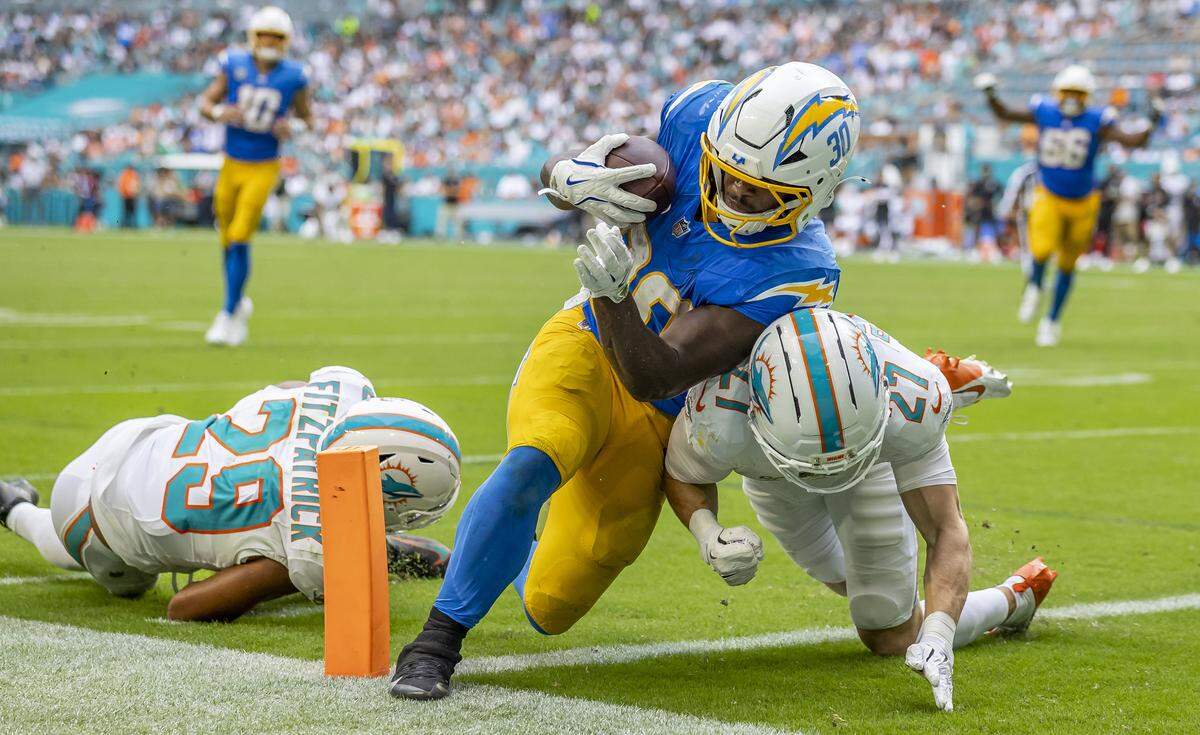 Los Angeles Chargers running back Kimani Vidal (30) scores a touchdown as Miami Dolphins cornerback Ethan Bonner (27) and free safety Minkah Fitzpatrick (29) fail to stop him in the second half of their NFL game at Hard Rock Stadium on Sunday, Oct. 12, 2025, in Miami Gardens, Fla.