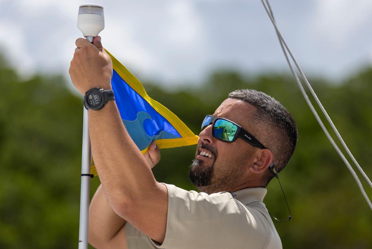Miami-Dade Officer David Loriga works to hang a Fly High, Bird flag on a patrol boat at the Black Point Park and Marina on Friday, Aug. 30, 2024, in Homestead, Fla.