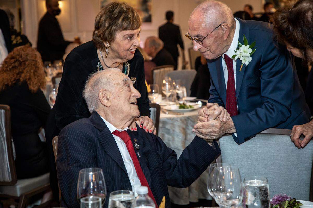Sam Ron, left, and Yitzhak Waksal meet for the first time in nearly 80 years at the United States Holocaust Memorial Museum’s “What You Do Matters” South Florida Dinner on March 20, 2022 in Boca Raton. The two were in the same labor camp during the Holocaust and recognized each other at the dinner. Ron’s wife Bilha looks on.