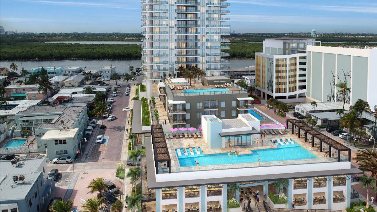 An architectural rendering shows a residential and commercial complex that would replace nine small motels along the Broadwalk in Hollywood beach. A two-story beach club and restaurant would face the Broadwalk, with a high-rise apartment tower behind it, separated by North Surf Road. A parking garage that’s part of the project can be seen at far right near two existing motels whose owners have not agreed to sell to the developer.