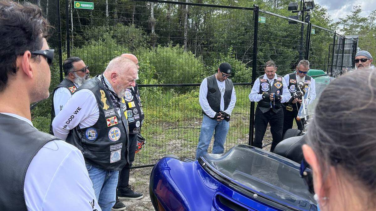 Archbishop of Miami Thomas Wenski (left) prayed with members of the Knights on Bikes ministry at the entrance of Alligator Alcatraz, South Florida’s immigrant detention center in the Everglades.