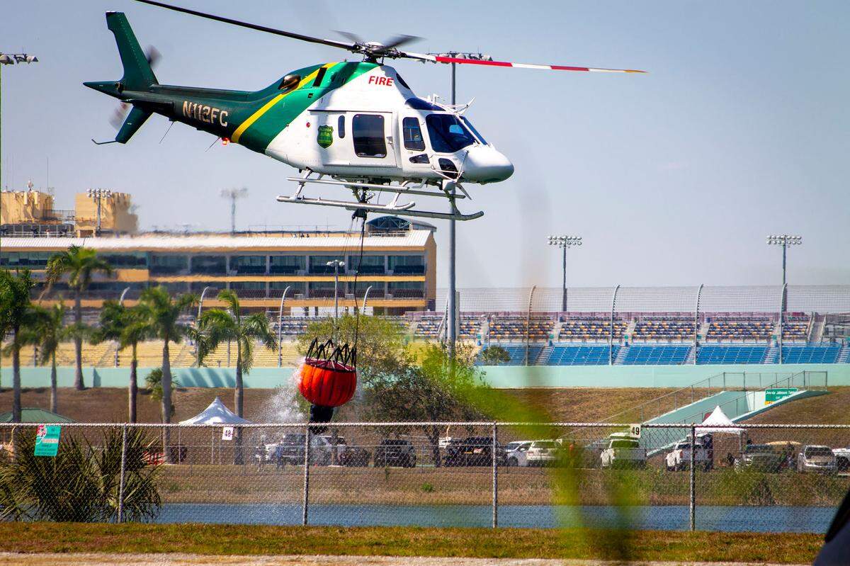 Homestead, FL- A Florida Forest Service Helicopter gathers water from a retention pond behind Homestead Speedway Friday, March 21, 2025, to fight nearby wildfires in south Miami-Dade County.