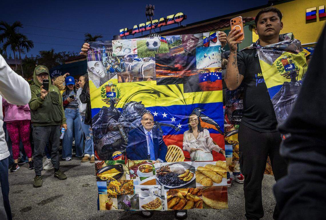 A man displays a banner with a picture of opposition leaders María Corina Machado and Edmundo González Urrutia, as he joined a group of Venezuelans exiles living in South Florida celebrating outside of El Arepazo in Doral, Florida, after the United States attacked Venezuela and captured Venezuelan leader Nicolás Maduro, on Jan. 3, 2026.