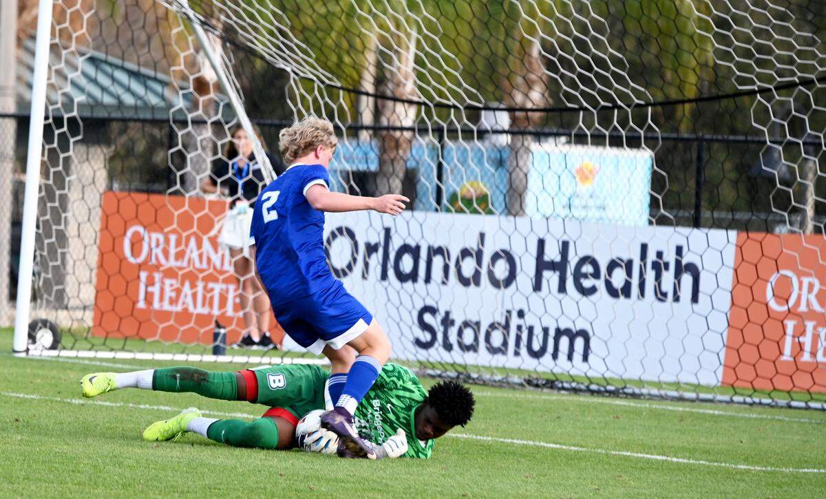 BridgePrep Village Green junior goalkeeper Kemal Mattocks makes a diving save against Fort Myers Canterbury while Ben Tomlinson looks to get a rebound opportunity during a Class 1A boys soccer state semifinal on Friday at the Lake Myrtle Soccer Complex in Auburndale.