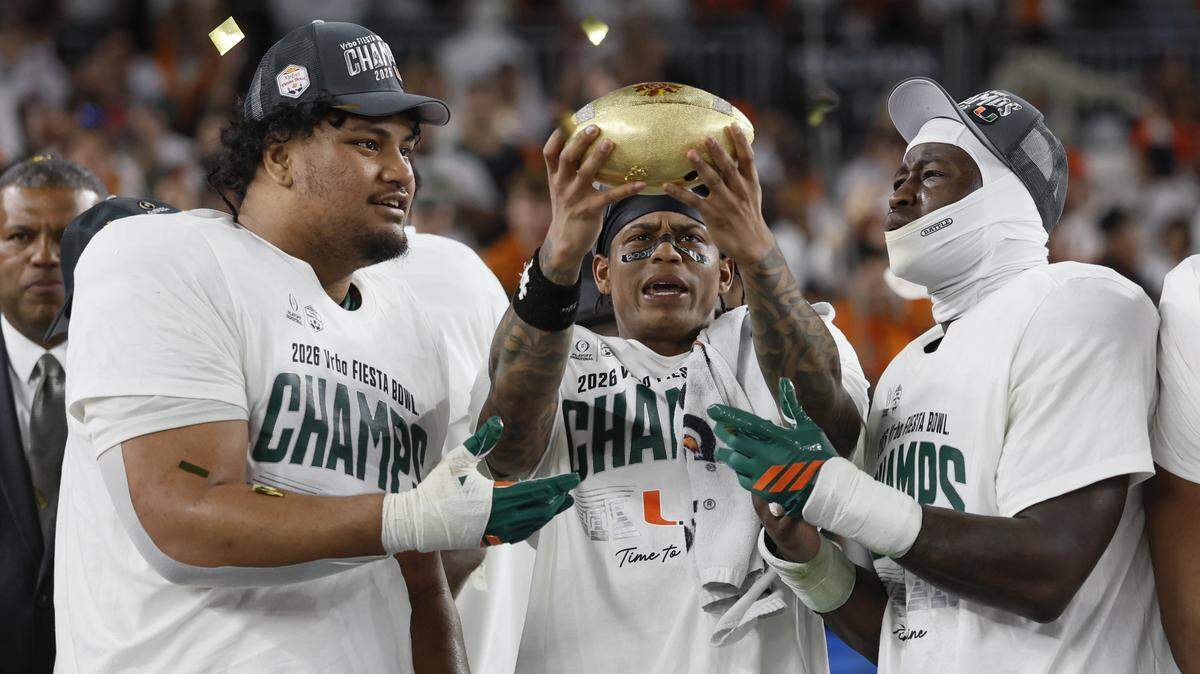 Miami Hurricanes offensive lineman Francis Mauigoa (61), wide receiver Keelan Marion (0), and linebacker Mohamed Toure (1), raises the diamond-encrusted football that is fully removable from the Fiesta Bowl Trophy, as the team celebrates on stage after defeating the Mississippi Rebels in the College Football Playoff semifinal at the Fiesta Bowl at State Farm Stadium on Friday, January 9, 2026 in Glendale, Arizona.