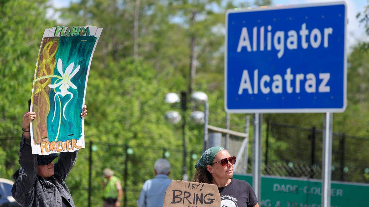 Ashlie Soto of Lehigh acres and Jill Cicero of Naples holds up signs outside of Alligator Alcatraz on Saturday, July 12, 2025 in Ochopee.