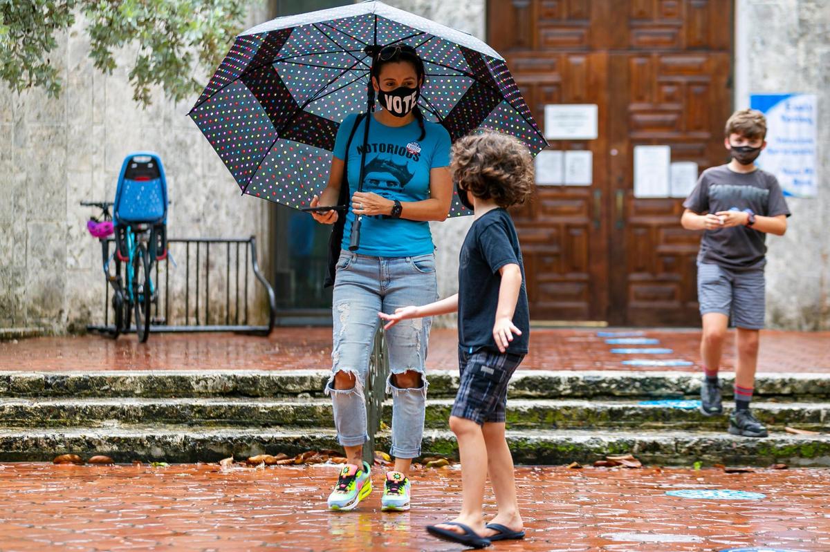 Sandra Portal-Andreu, 40, and her two sons, Gabo, 7, center, and Julian, 11, right, leave the Coral Gables Branch Library after voting on the first day of early voting in Coral Gables, Florida on Monday, August 3, 2020.