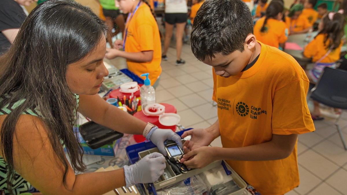 Javier Fornaris-12, takes a reading of his blood sugar with the assistance of a nurse at Camp Roaring Sun sponsored by Nicklaus Children's Hospital on Monday, July 9, 2018.