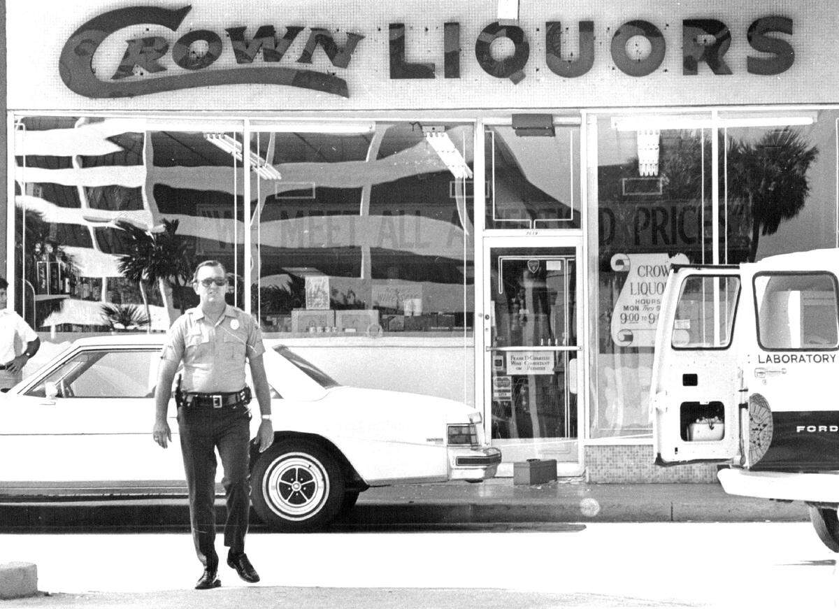 File photo from July 11, 1979, at Dadeland Mall. Police and crime lab technicians pore over Crown Liquors in the parking lot after gunmen armed with sub machine guns sprayed more than 60 rounds inside the store, killing a rival drug dealer and his bodyguard and wounding two bystander employees.