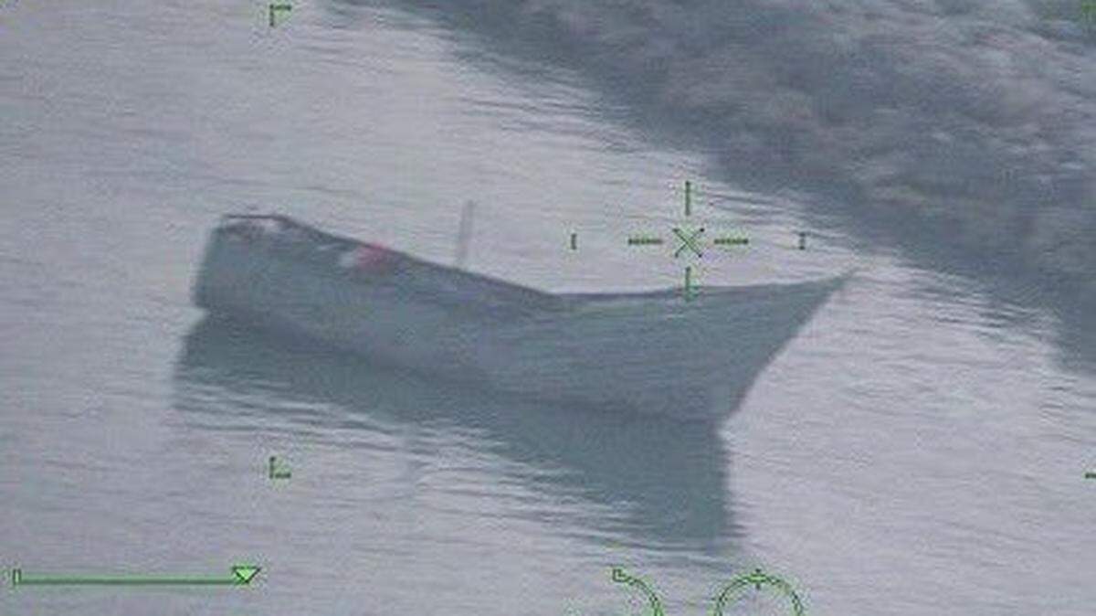 A migrant boat floats in shallow water just off a rocky beach in Duck Key Monday night, March 18, 2024. The U.S. Border Patrol said there were 21 men and three women from Cuba on board the vessel.