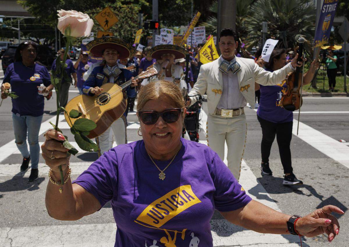 Elsa Rodriguez, a janitor, walks across the street followed by a mariachi band during a march held by janitors employed by UM's cleaning contractor, ABM, on Monday, Aug. 18, 2025, outside of the University of Miami in Coral Gables, Fla. 