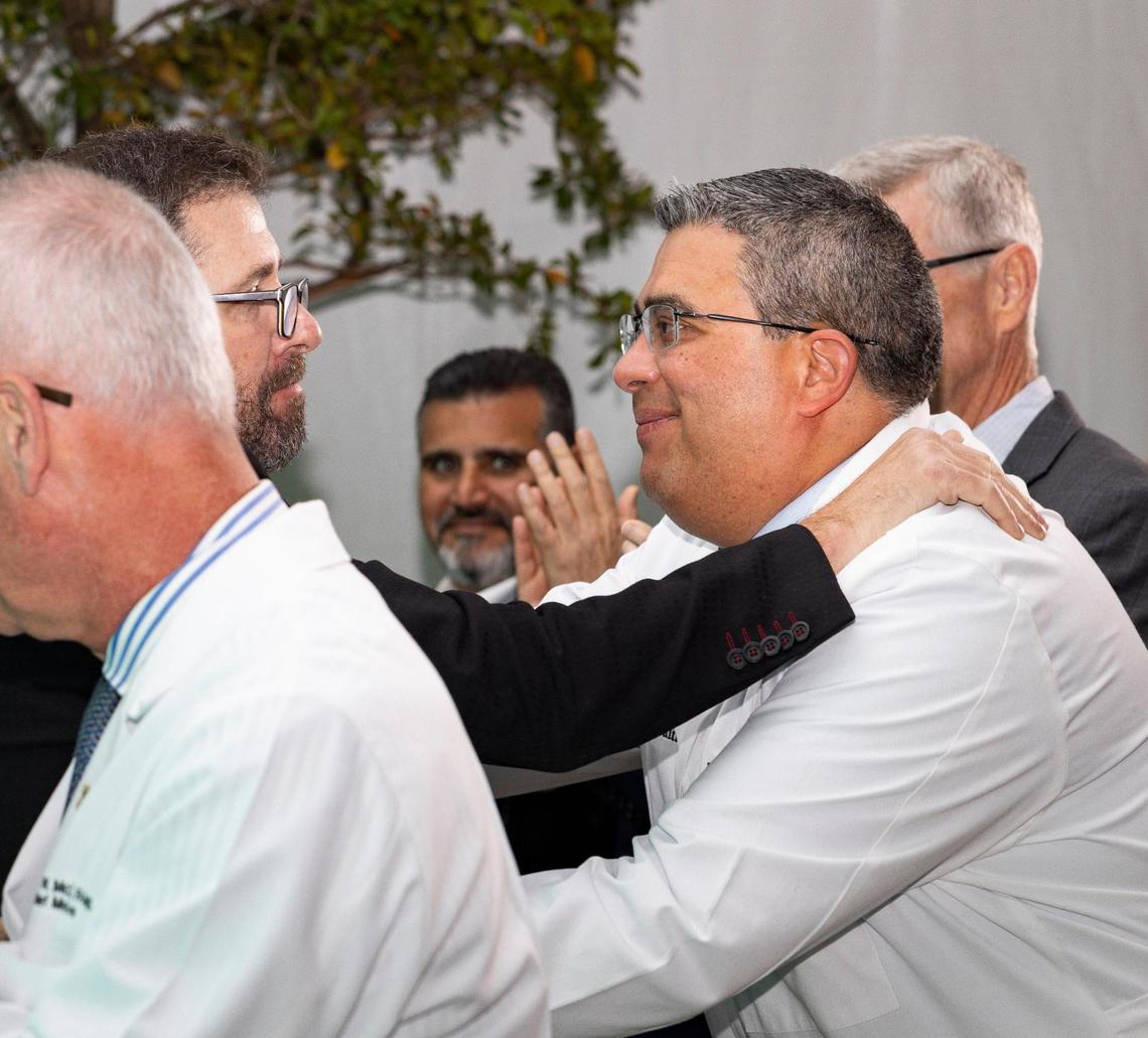 Sebastian Krys, 22-time Grammy and Latin Grammy award-winner and Parkinson’s patient, left, embraces his doctor, Diego Torres-Russotto, during a ceremony recognizing Ken Griffin, Citadel CEO, for his donation to the Miami Neuroscience Institute on Tuesday, March 19, 2024, at the Baptist Health Baptist Hospital in Miami, Fla.