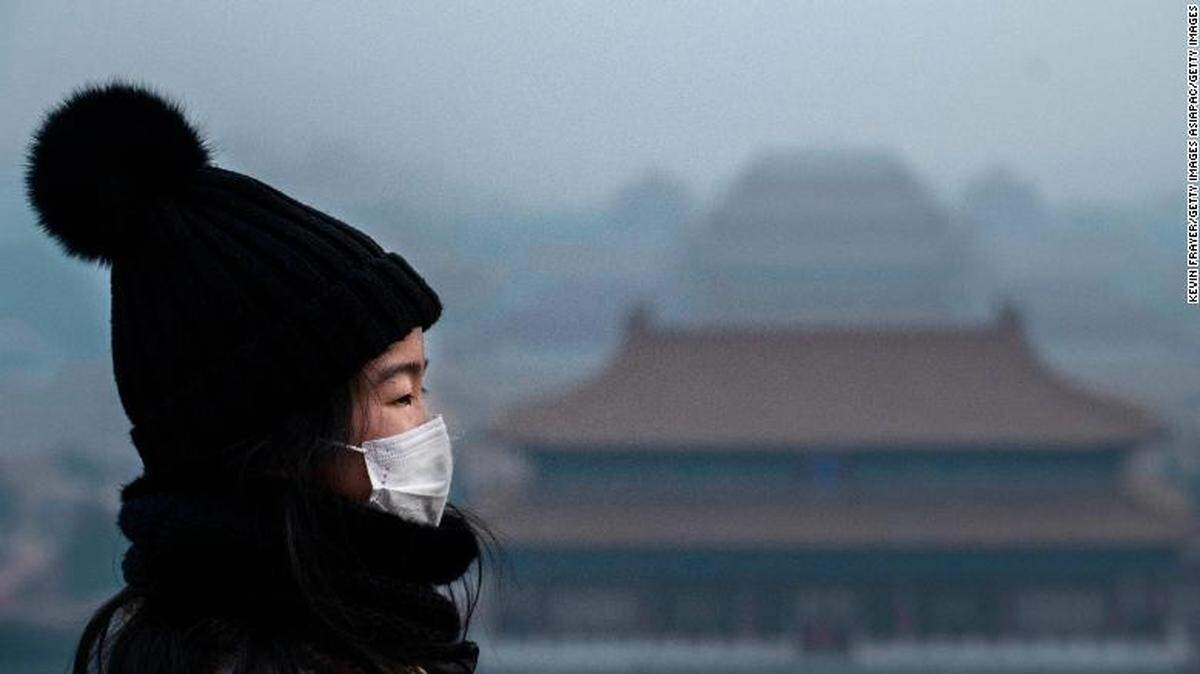 A Chinese girl wears a protective mask as she stands on an overlook towards the Forbidden City, authorities closed during the Chinese New Year holiday in January.