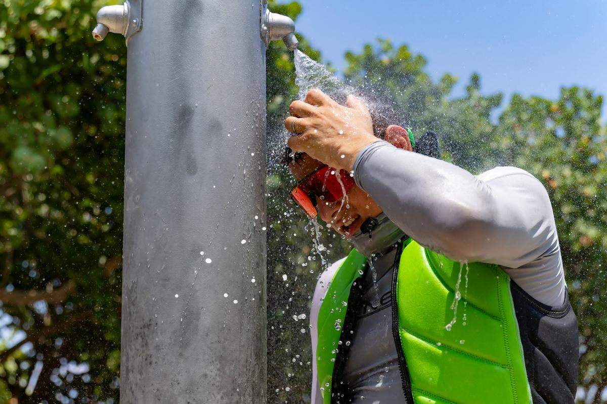 Beachgoer Sergei lazovskiy cools off under the shower on a sunny and hot day at the Haulover Park beach on May 28, 2024. There have been regular heat advisories throughout the summer so far in South Florida.