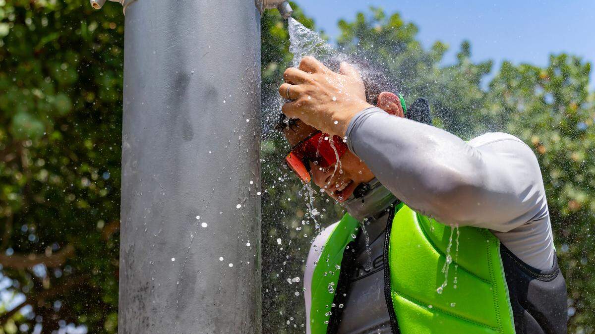 Beachgoer Sergei lazovskiy cools off under the shower after enjoying the sunny and hot day at the Haulover Park Beach at on Tuesday, May 28, 2024, in Miami Beach, Florida.