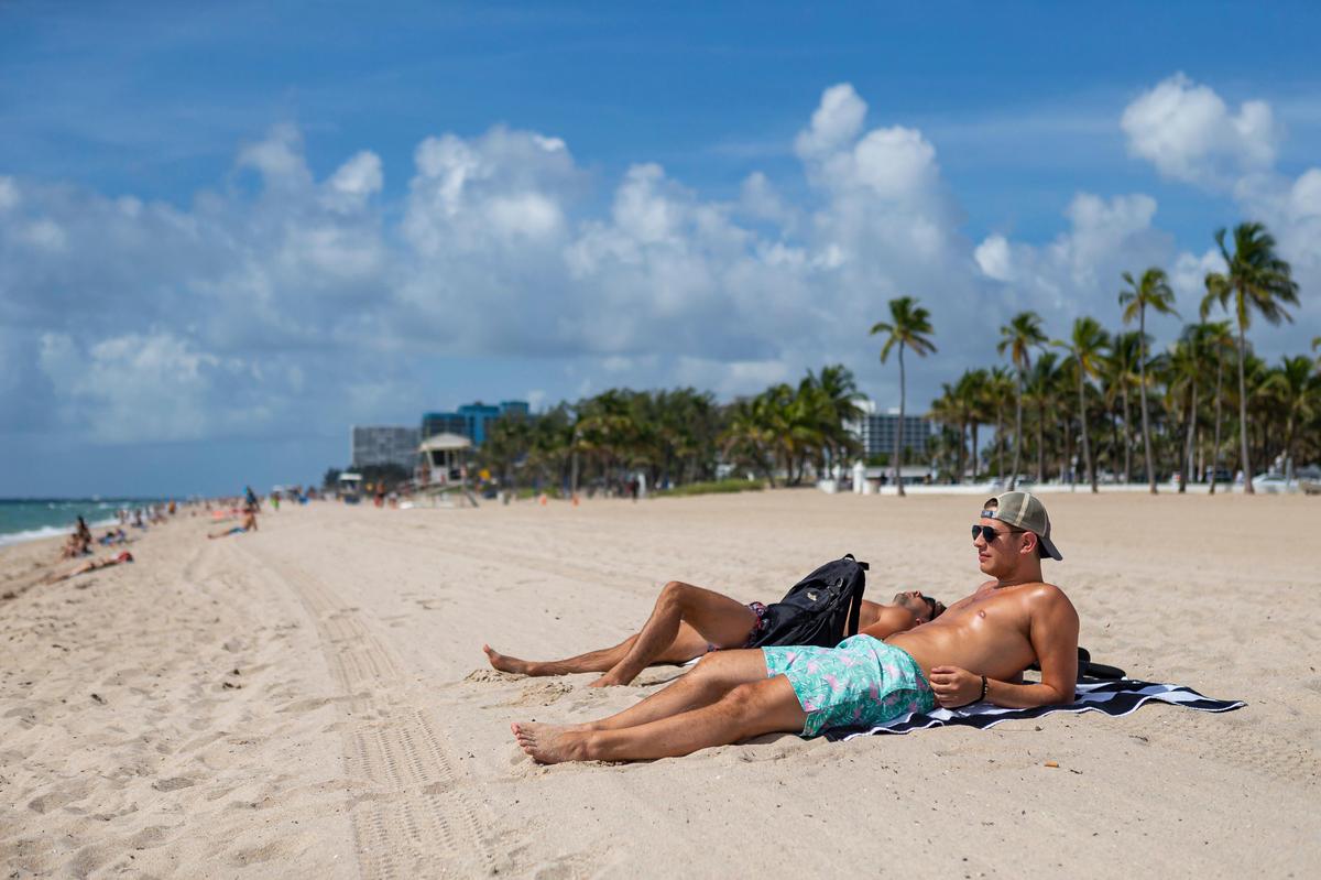 Tom Vankuilenburg, 26, right, and his friend, Shane Connell, 27, sunbathe at Las Olas Beach in Fort Lauderdale, Florida on Saturday, May 30, 2020.