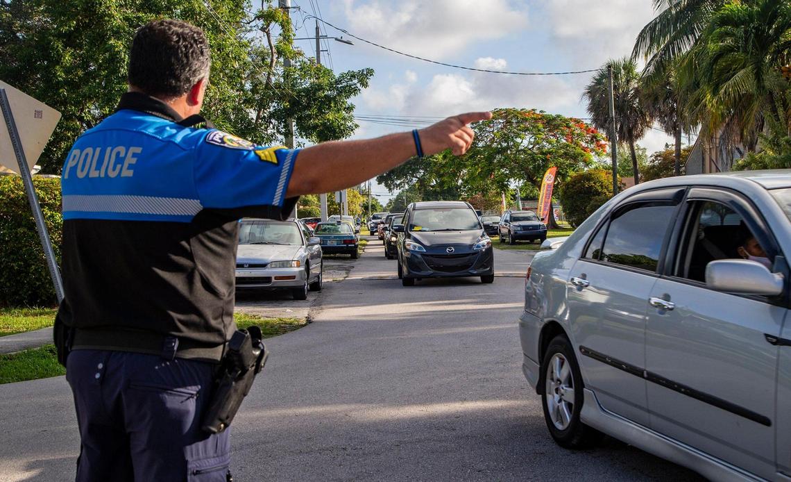 Sgt. Alex Morales with the North Miami Beach Police Department directs cars lined up along Northeast Fourth Avenue during a Publix gift card distribution drive-thru at Uleta Park Community Center on Saturday, June 5, 2021.