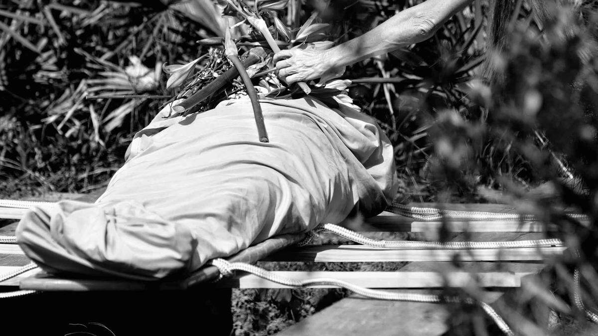 Un grupo de dolientes depositando flores sobre un cadáver envuelto en un sudario antes de depositarlo en una tumba en el cementerio Heartwood Preserve Conservation, cerca de Tampa, Florida.