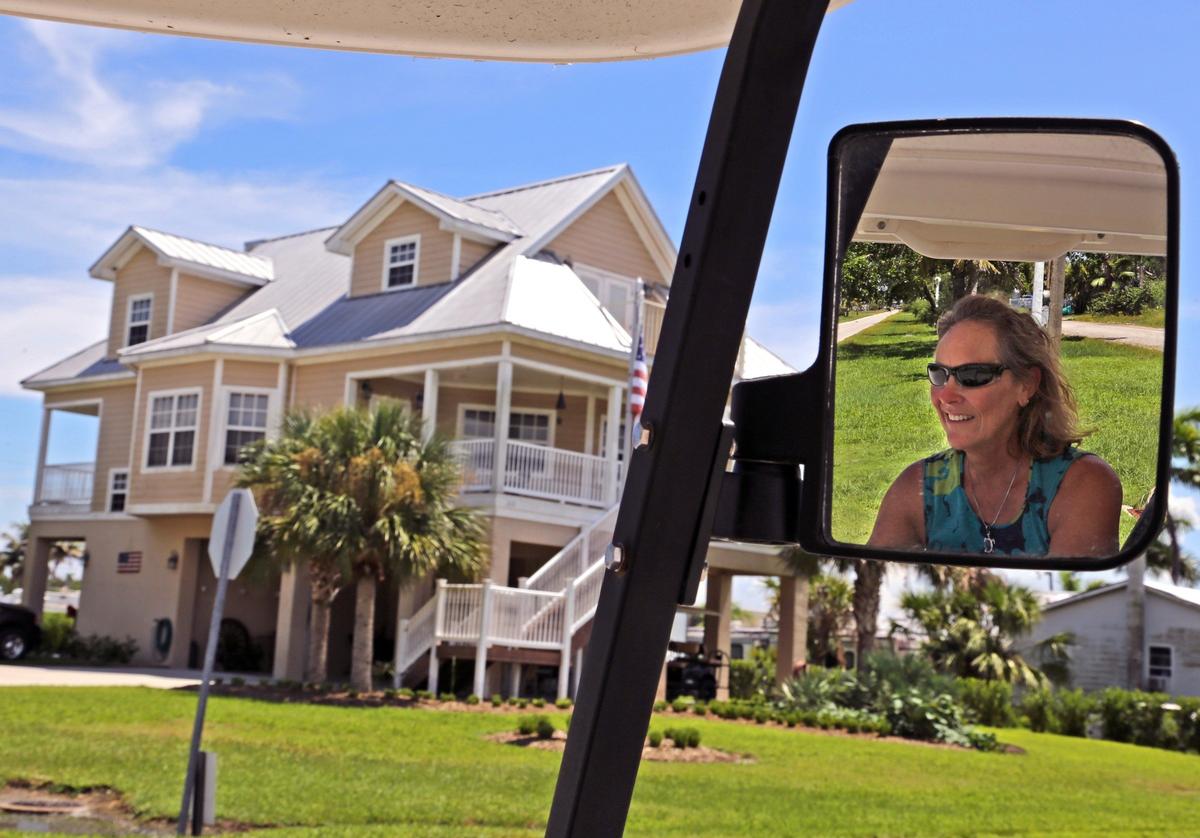 Kathy Brock, editor of the Mullet Rapper, Everglades City’s local paper, drives her golf cart past one of the largest stilt homes in the small town on Thursday.
