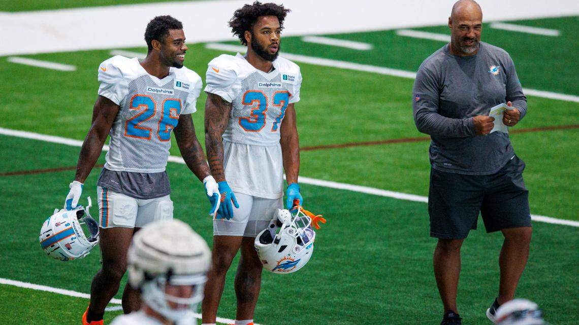 Miami Dolphins Eric Studesville associate head coach and running backs coach, running backs Salvon Ahmed (26) Myles Gaskin (37) look from the sideline during NFL football training camp at Baptist Health Training Complex in Hard Rock Stadium on Thursday, August 18, 2022 in Miami Gardens, Florida.