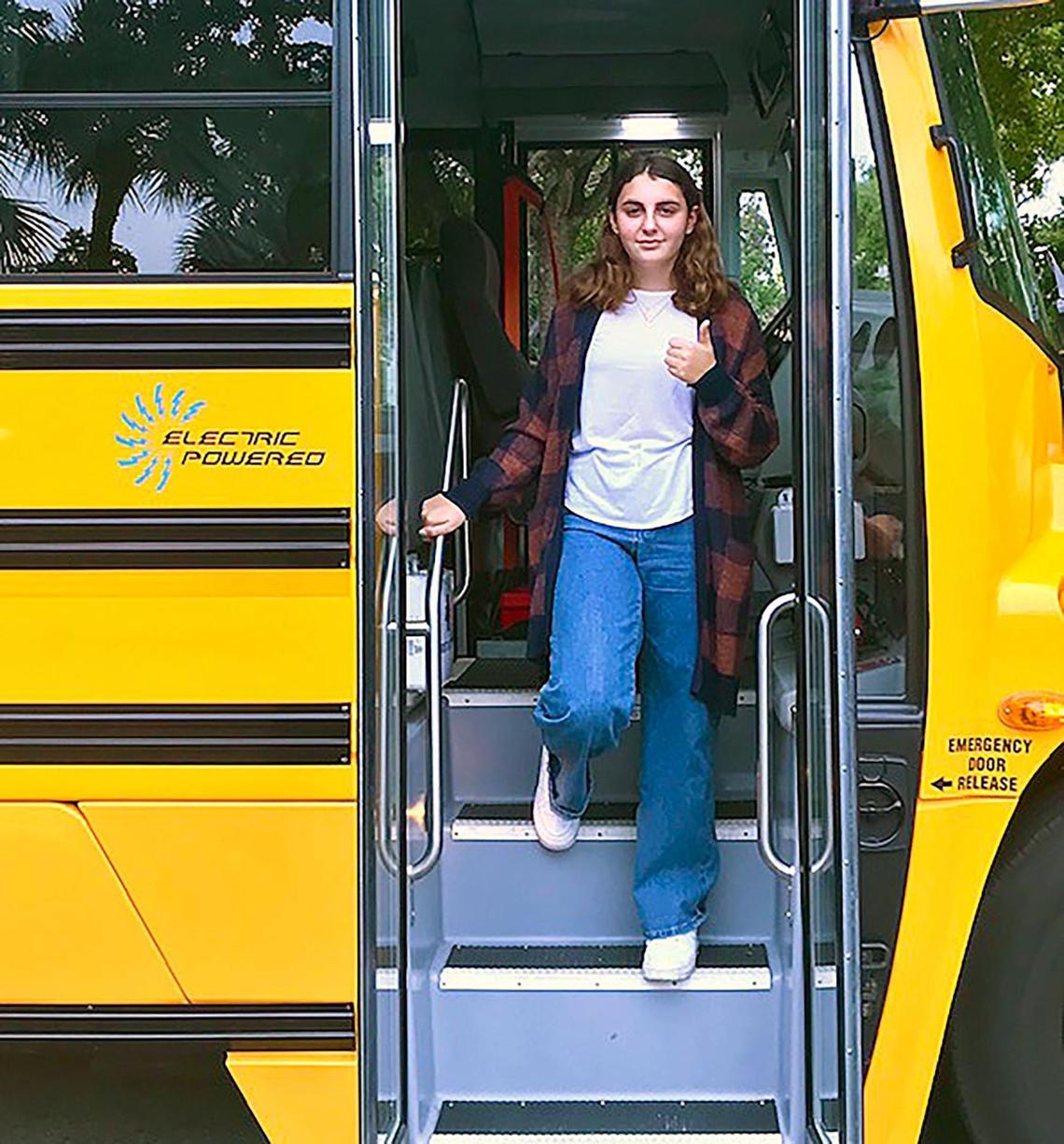 MAST Academy student Holly Thorpe steps off a Lion C electric school bus after a clean, quiet demonstration ride in Miami. Thorpe’s science fair project showing hazardous emissions levels inside Miami-Dade Schools’ diesel buses spurred the district to apply for funding to convert to a fleet powered by renewable energy.