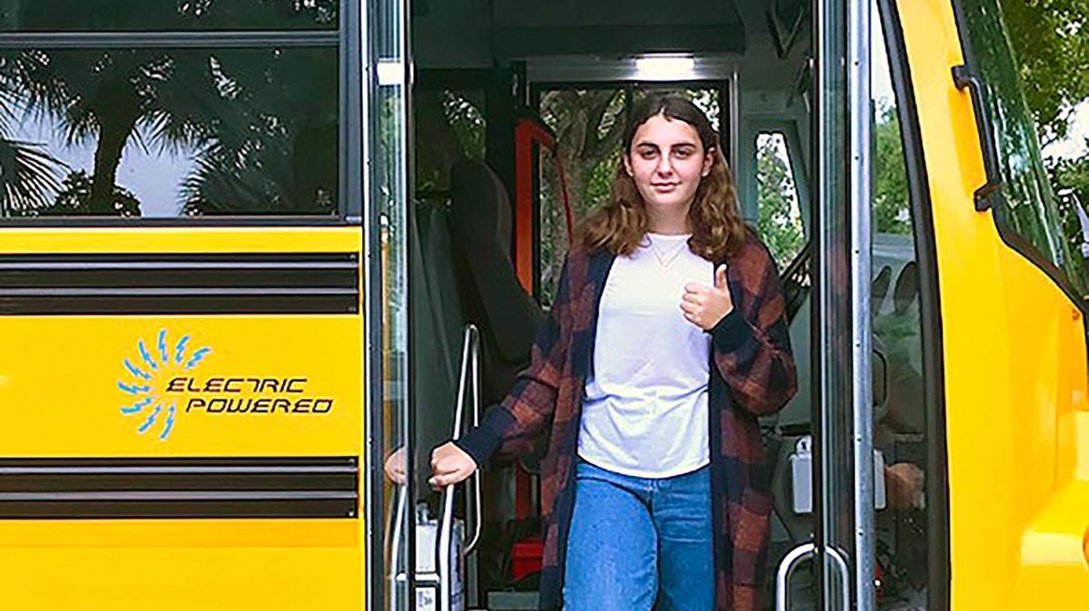 MAST Academy student Holly Thorpe steps off a Lion C electric school bus after a clean, quiet demonstration ride in Miami. Thorpe’s science fair project showing hazardous emissions levels inside Miami-Dade Schools’ diesel buses spurred the district to apply for funding to convert to a fleet powered by renewable energy.