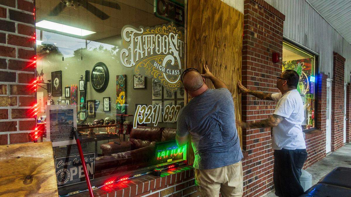 David Parker, left, and Jesse Cuen put up plywood boards to the windows and doors at the High Class Ink Studios in Palm Bay, in Northeast Florida in preparation for Hurricane Milton on Oct. 8, 2024.