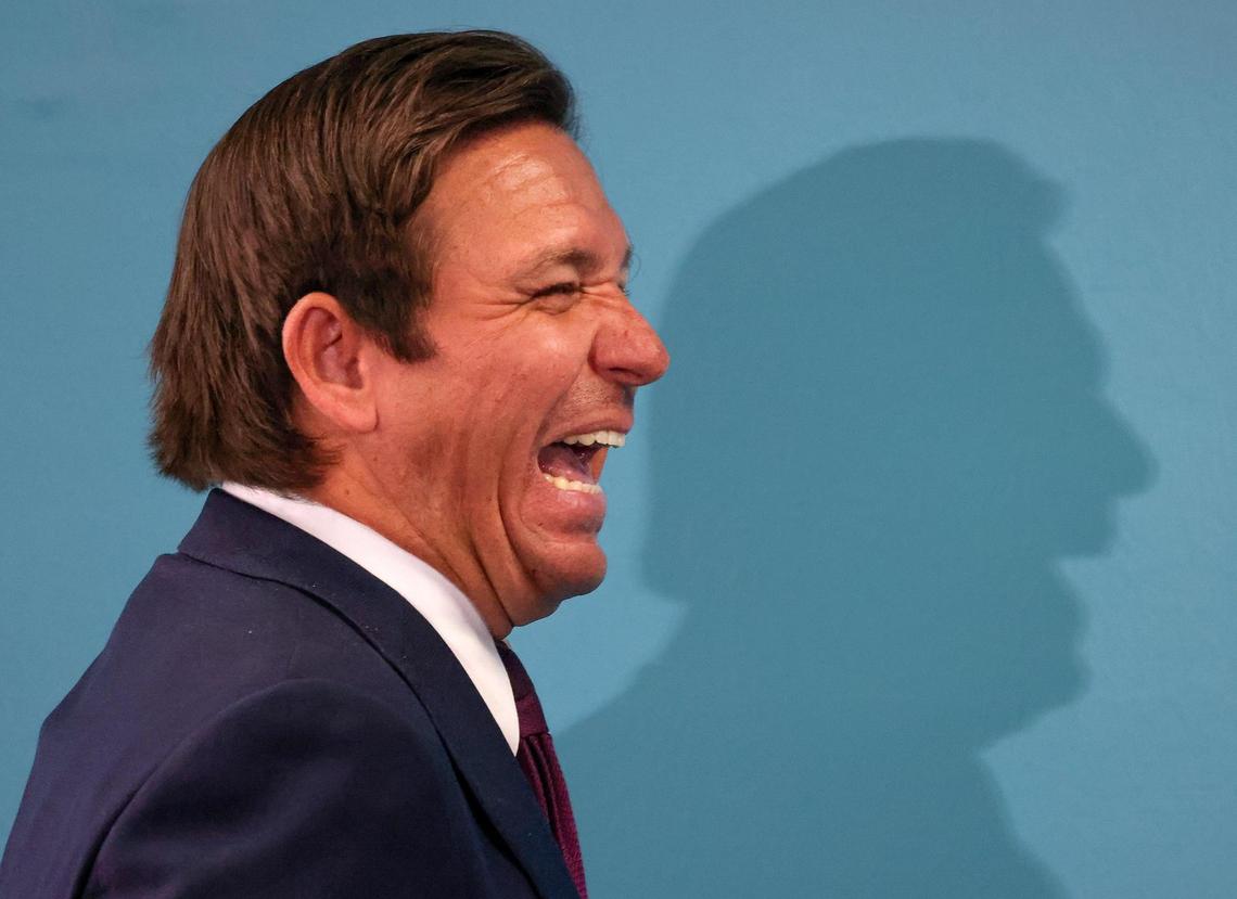 Gov. Ron DeSantis breaks into laughter during remarks by Florida Department of Health Surgeon General Dr. Joseph Ladapo at a press conference in Miami inside the Rhode Building on Tuesday, May 6, 2025.