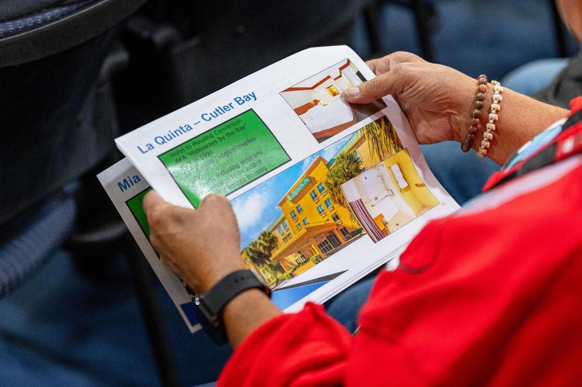 A woman holds a packet explaining the Miami-Dade County Homeless Trust’s plan to convert a La Quinta Inn motel in Cutler Bay into affordable apartments for the formerly homeless during a town council forum on Nov. 29, 2023.