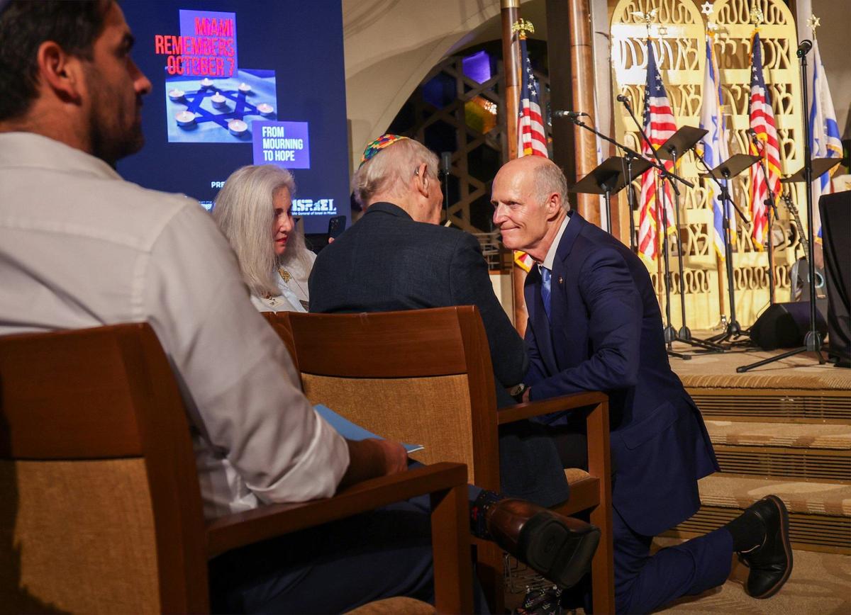 Holocaust survivor David Schechter, center, and Florida Senator Rick Scott, right, shake hands. The Miami Jewish community gathered at Temple Beth Sholom in remembrance of those who perished in the events of October 7, 2023.