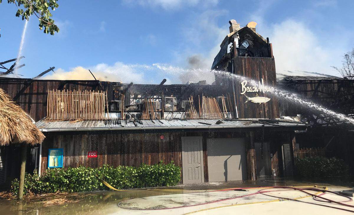 Key Largo Volunteer Fire Department firefighters spray a hose on the smoldering facade of Bungalows Key Largo, a resort at mile marker 99 that caught fire early Sunday morning, May 5, 2019.