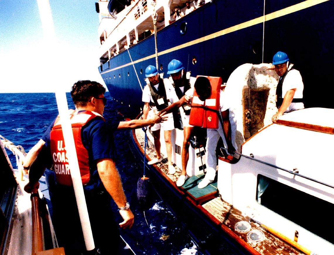 A Coast Guard boat approaches a Cuban rafter picked up in the Florida Keys by Queen Elizabeth’s yacht Britannia, rear.