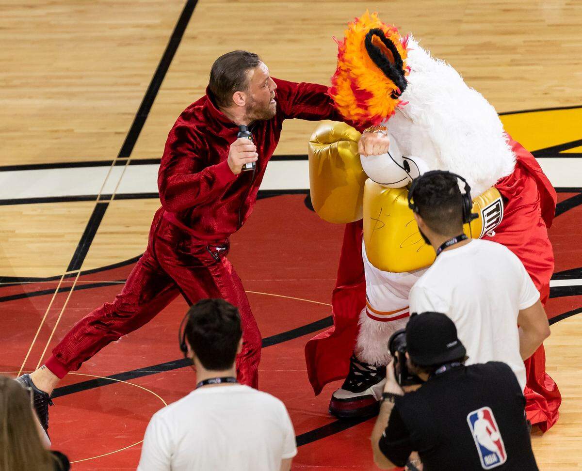 El luchador de artes marciales mixtas Conor McGregor golpeando a la mascota del Miami Heat "Burnie" durante un sketch en un tiempo muerto del cuarto partido de las Finales de la NBA entre el Miami Heat y los Denver Nuggets en Kaseya Center el viernes 9 de junio de 2023, en el downtown de Miami, la Florida.
