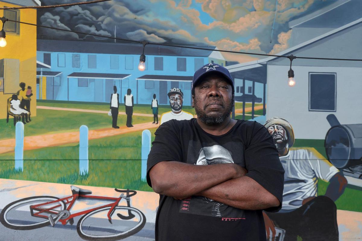 Terrence “Uncle Tee” Smith stands by the mural painted on the side of this barbecue restaurant near the street named after his brother, Lance Cpl. Kirk Hall Smith.
