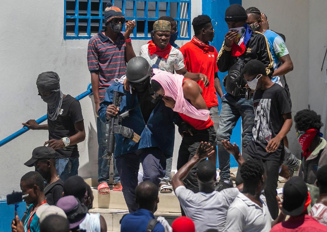 A police officer breaks an imprisoned fellow officer from the Delmas 33 police station lockup during a protest by a disgruntled sector of the Haitian police force known as Fantom 509, in Port-au-Prince, Haiti, Wednesday, March 17, 2021. The protests started when officers and police academy cadets marched toward police headquarters to demand that the bodies of several officers killed during a raid last week on the Village of God shantytown be recovered from the gang still holding them.