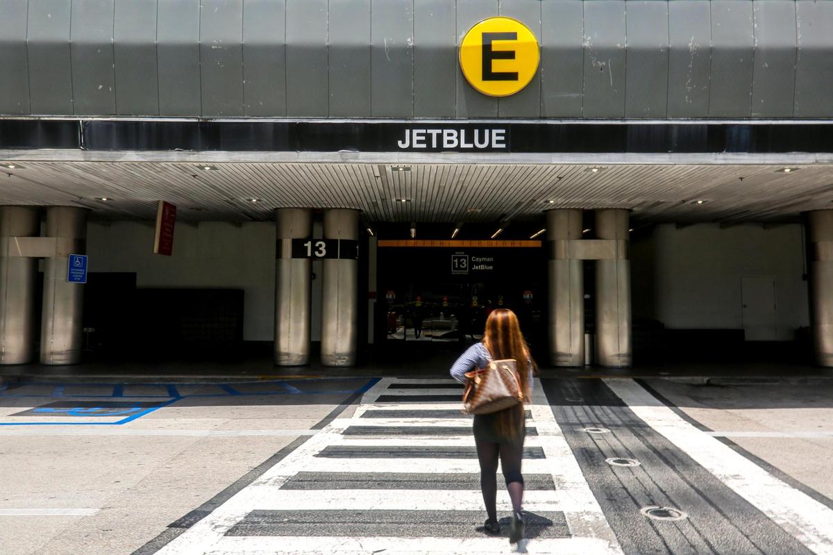 A woman crosses the street toward Concourse E where low-cost airline carrier jetBlue now operates from at Miami International Airport in Miami, Florida on Friday, August 6, 2021.
