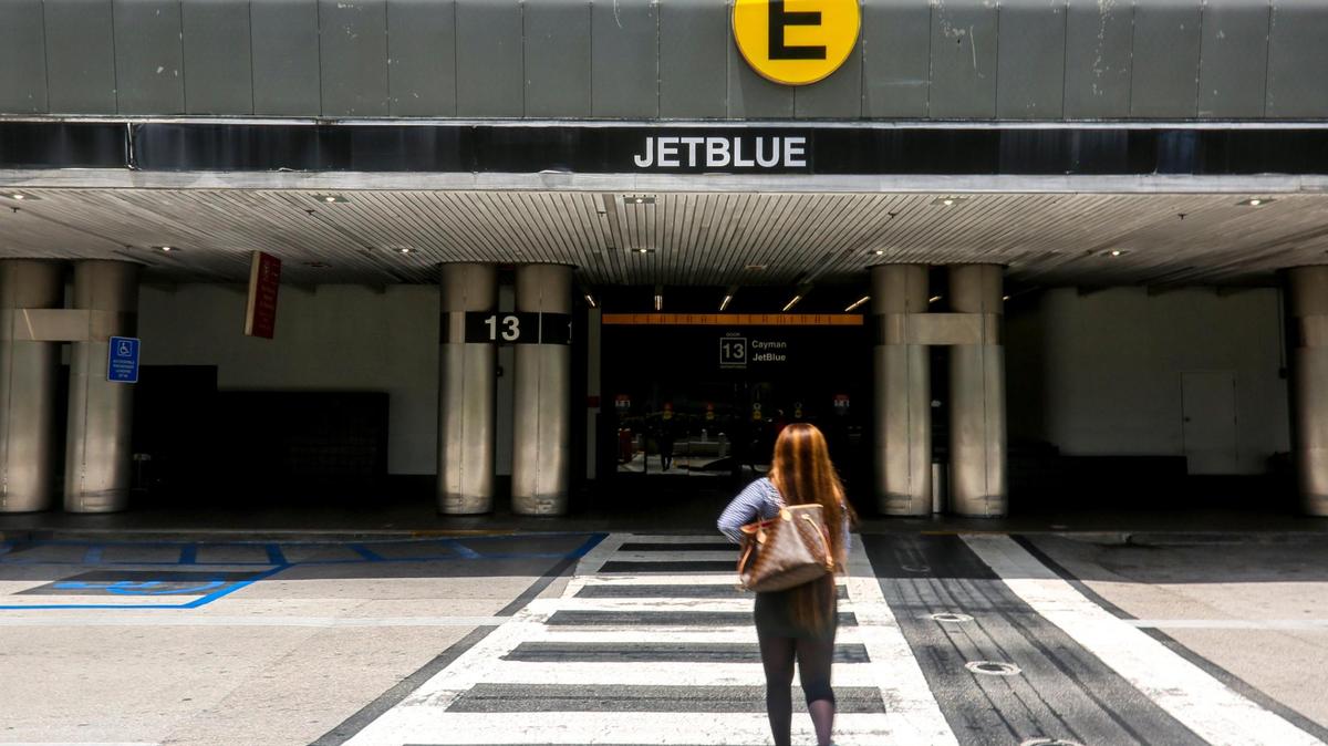 A woman crosses the street toward Concourse E where low-cost airline carrier jetBlue now operates at Miami International Airport in Miami on Friday, August 6, 2021.