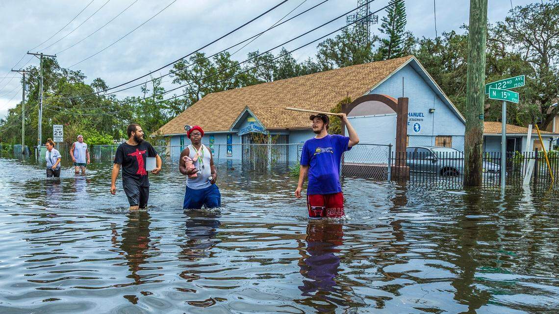 Residents walk through a flooded street in North Tampa, on Thursday, Oct. 10, 2024, a day after Hurricane Milton crossed Florida’s Gulf Coast. South Florida’s Columbus Day weekend weather could see lower temperatures as a result of Milton, but a front is bringing thunderstorms to the Miami-Dade, Broward areas on Oct. 12-13.