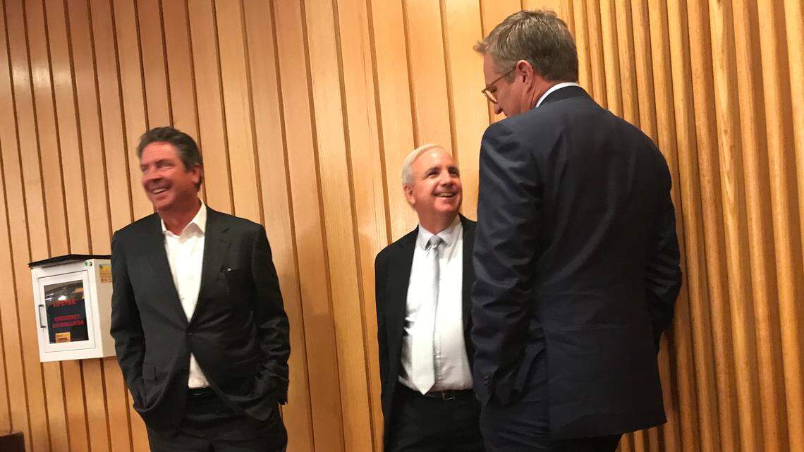 Dan Marino laughs at a conversation between Miami-Dade Mayor Carlos Gimenez, center, and Dolphins CEO Tom Garfinkel after the county commission approved an expanded subsidy deal for the team in exchange for moving its training and headquarters facility from Davie to a new complex in Miami Gardens costing as much as $75 million to build.