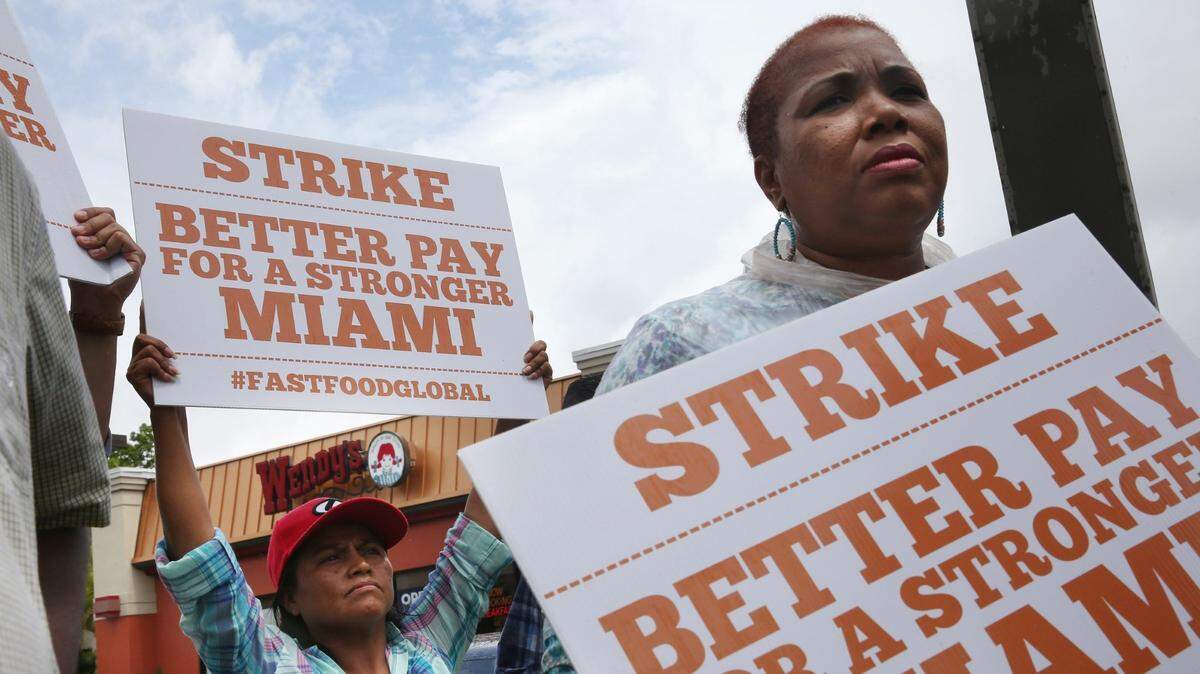 Maria Mejia (L) and others join in a fast-food workers’ protest demanding a $15 minimum wage and better working conditions in Miami in 2014.