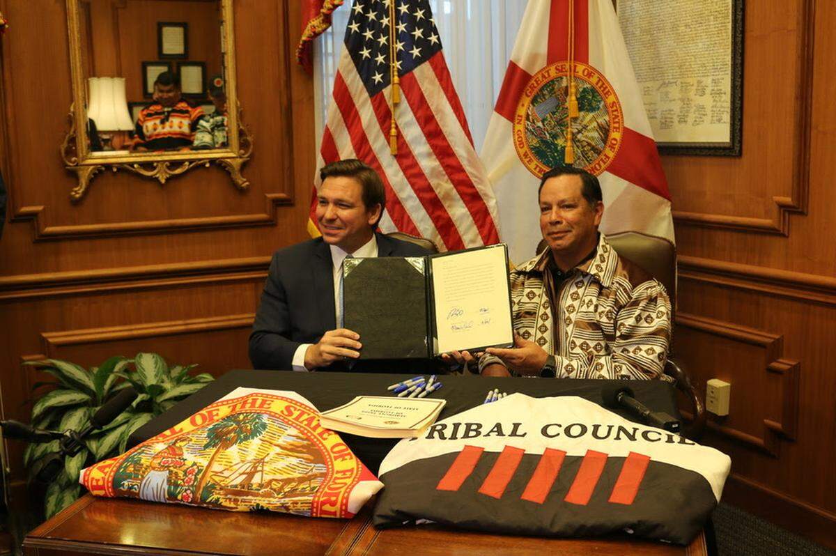 Gov. Ron DeSantis and Marcellus Osceola Jr., chairman of the Seminole Tribe, display the gaming compact that they signed in April.