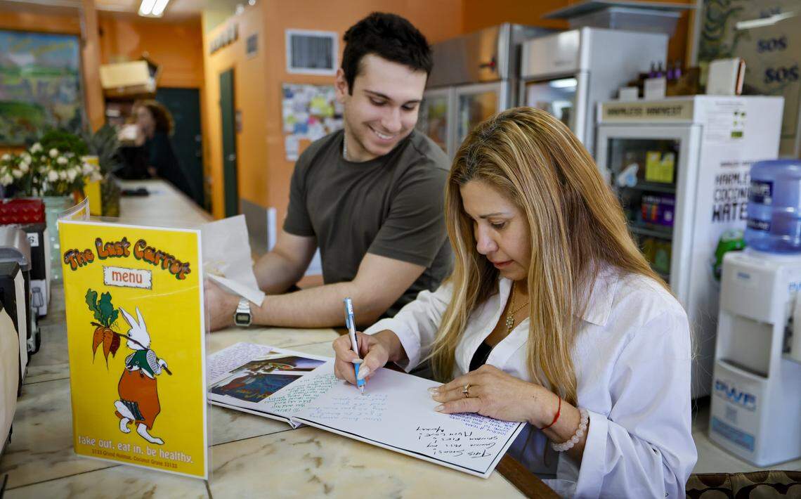 Josephine Diamond signs a photo album on display at The Last Carrot as her son Johnathan Wishinsky joins her for lunch.