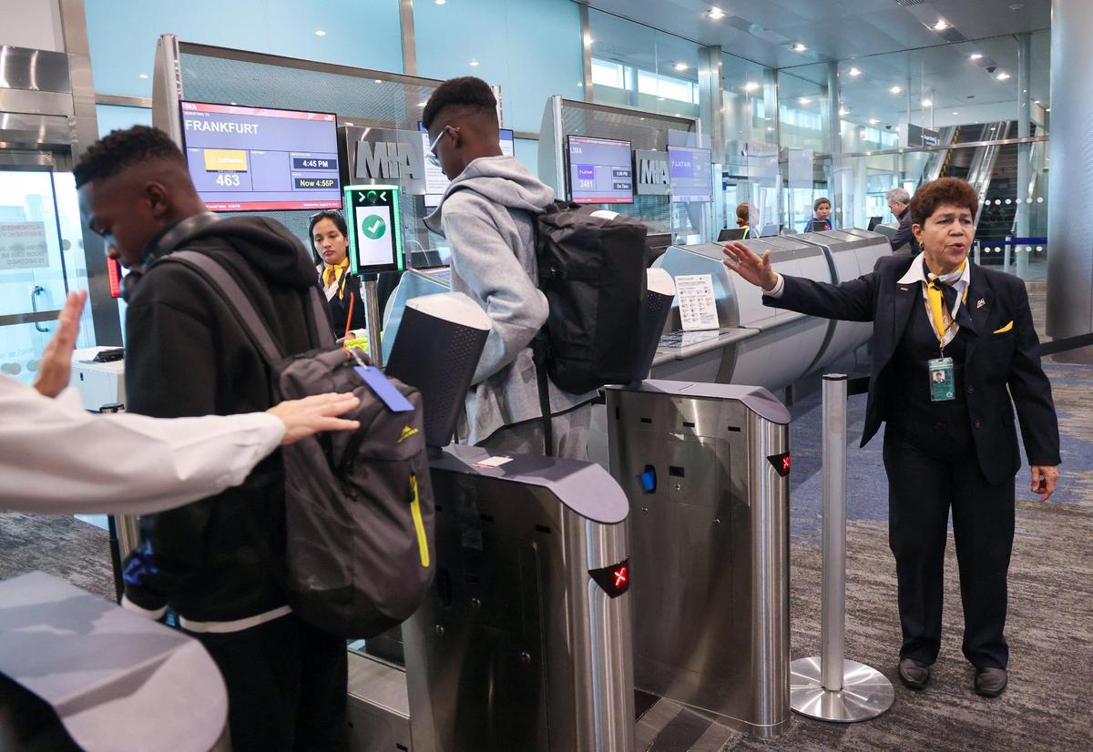Eva Burgos, passenger service agent, right, of Swissport, assist passengers before boarding Lufthansa flight 463 from Miami International Airport to Frankfurt on August 9, 2023, to get their pictures taken using the new facial-recognition technology at Gate J17.
