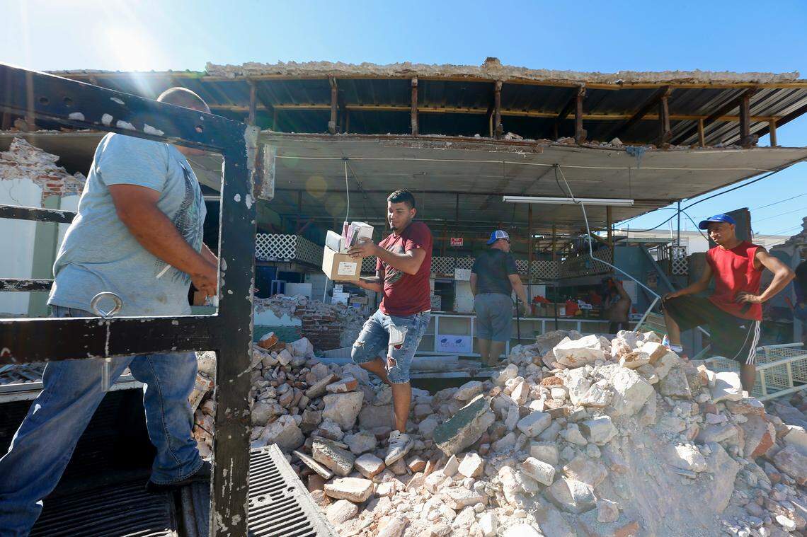 Jacob Pacheco, center, helps recover items from the damaged Ely Mer Mar Hardware store in Guanica, Puerto Rico, after a powerful 6.4 earthquake struck the island early Tuesday, January 7, 2020.