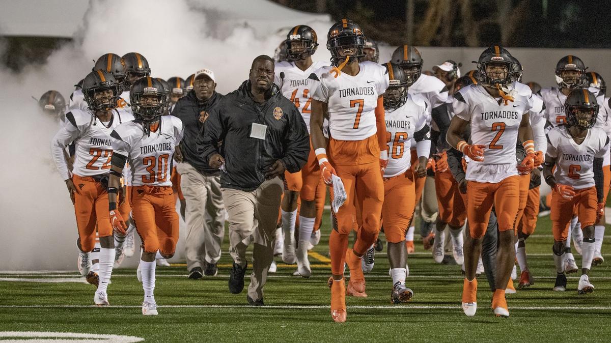 Associate Head Coach Ben Hanks runs onto the field with players to start the game as Booker T. Washington Tornadoes play the Bolles Bulldogs for Class 4A FHSAA State Championship Title at Daytona Stadium in Daytona Beach on Wednesday, December 11, 2019.