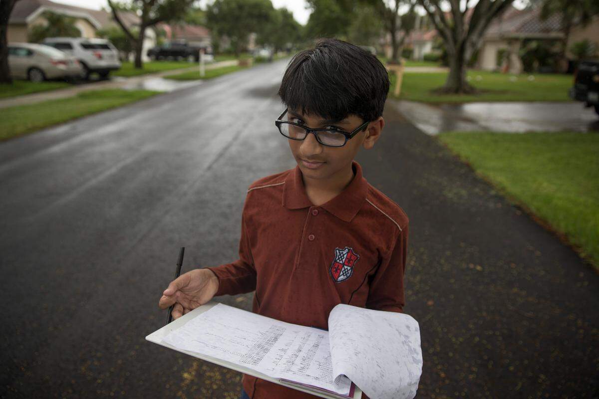 Muhammad Farooqui, 13, the son of Saima Farooqui, who is running in Broward's District 96 race in the state House of Representatives, reviews a list of registered Democrats in a neighborhood in Coconut Creek on Sunday, June 10, 2018.