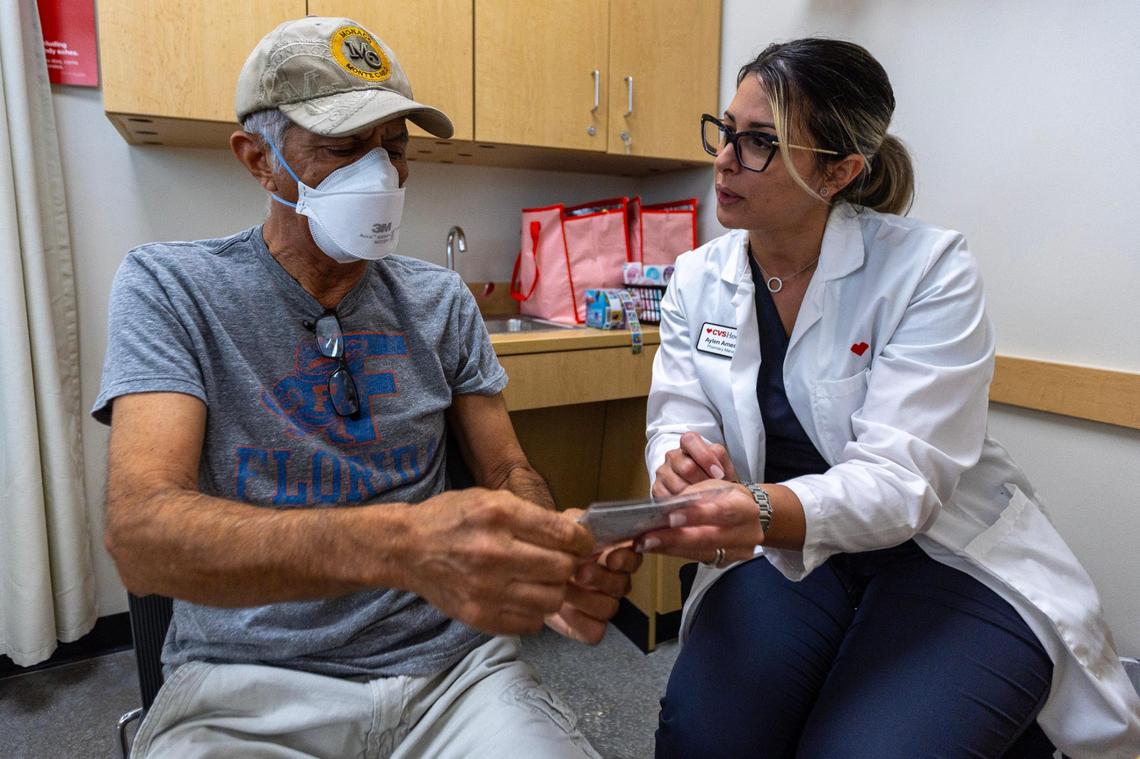 CVS Health Pharmacy Manager Aylen Amestoy answers questions related to the newest COVID-19 vaccine shot for Sasan Sowlati, 71, at a CVS in Miami, Florida, on Thursday, September 14, 2023.