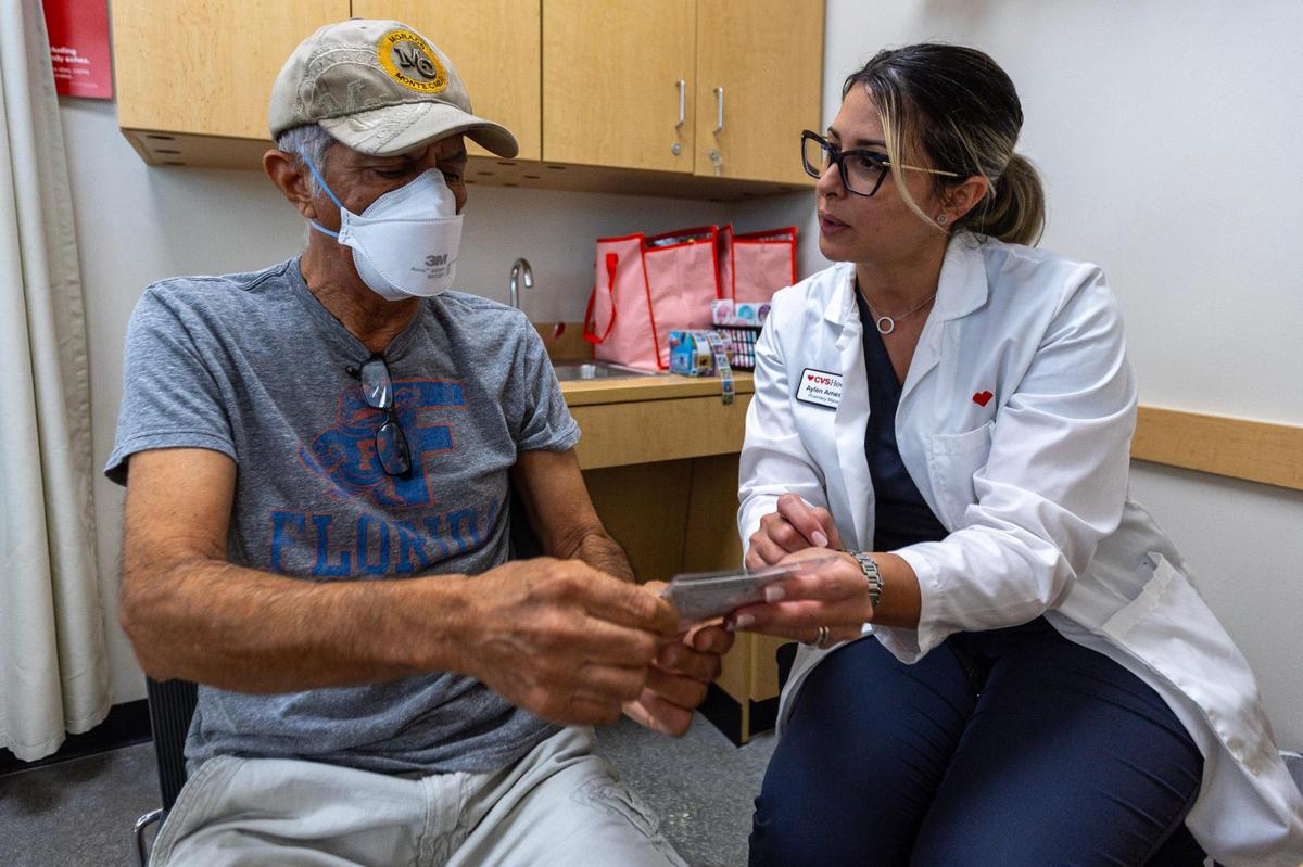 CVS Health Pharmacy Manager Aylen Amestoy answers questions related to the newest COVID-19 vaccine shot for Sasan Sowlati, 71, at a CVS in Miami, Florida, on Thursday, September 14, 2023.