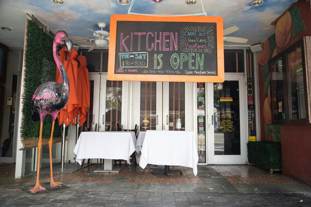 A sign indicating that the kitchen is open for takeout is posted in front of Ortanique restaurant in Coral Gables on Tuesday, April 7, 2020, as restaurants in Miami-Dade County remain closed to dine-in customers.