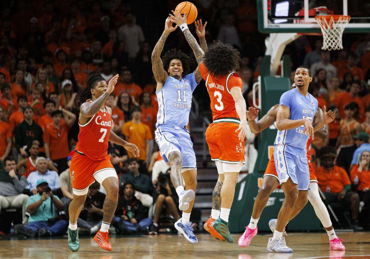 North Carolina Tar Heels forward Jonathan Powell (11) passes the ball over Miami Hurricanes guard Tre Donaldson (3) during the second half of a game on Tuesday, Feb. 10, 2026, at the Watsco Center in Coral Gables, Fla. The Miami Hurricanes won 75-66. 